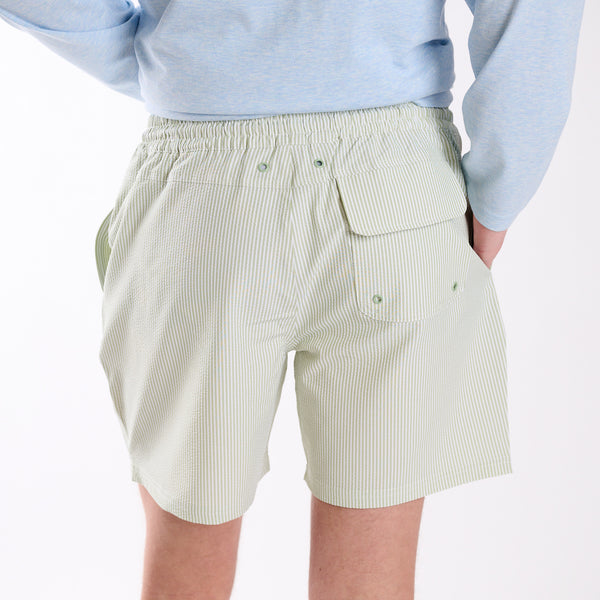 Person wearing light green shorts with a white background