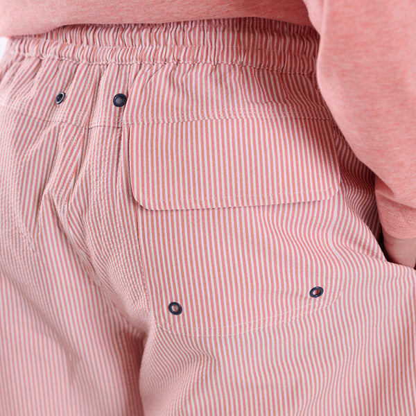 Close-up of pink striped pants with a pocket and buttons on a light pink background