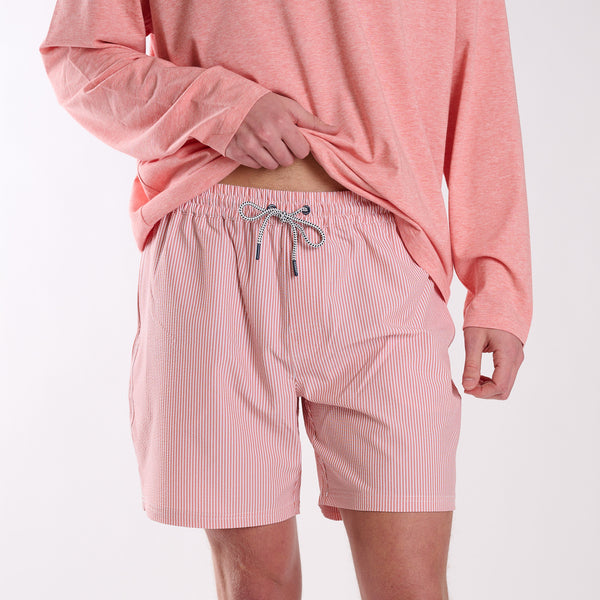 Person wearing a pink long-sleeve top and shorts on a white background