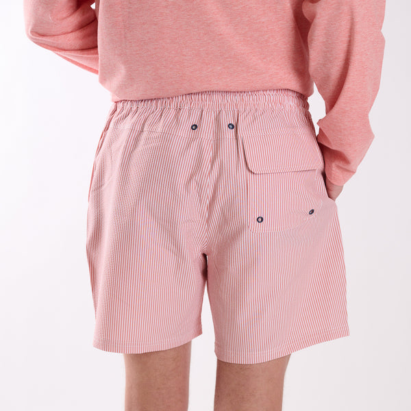 Person wearing pink striped shorts and a matching top on a white background