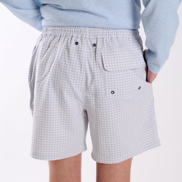 Back view of COAST seersucker gingham volley swim shorts in light blue and white with rear flap pocket and drainage grommets.