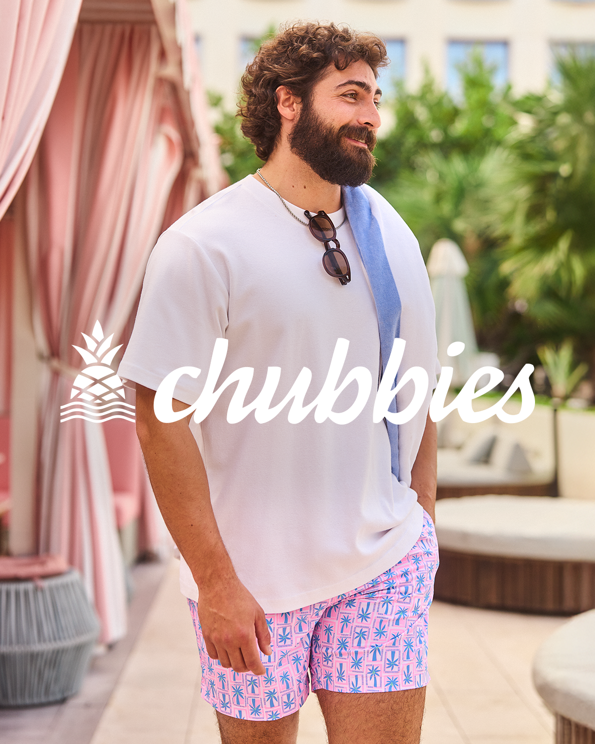 Man walking by pool cabanas in a Chubbies outfit.