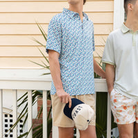 Two guys in spring outfits standing in front of a white fence.