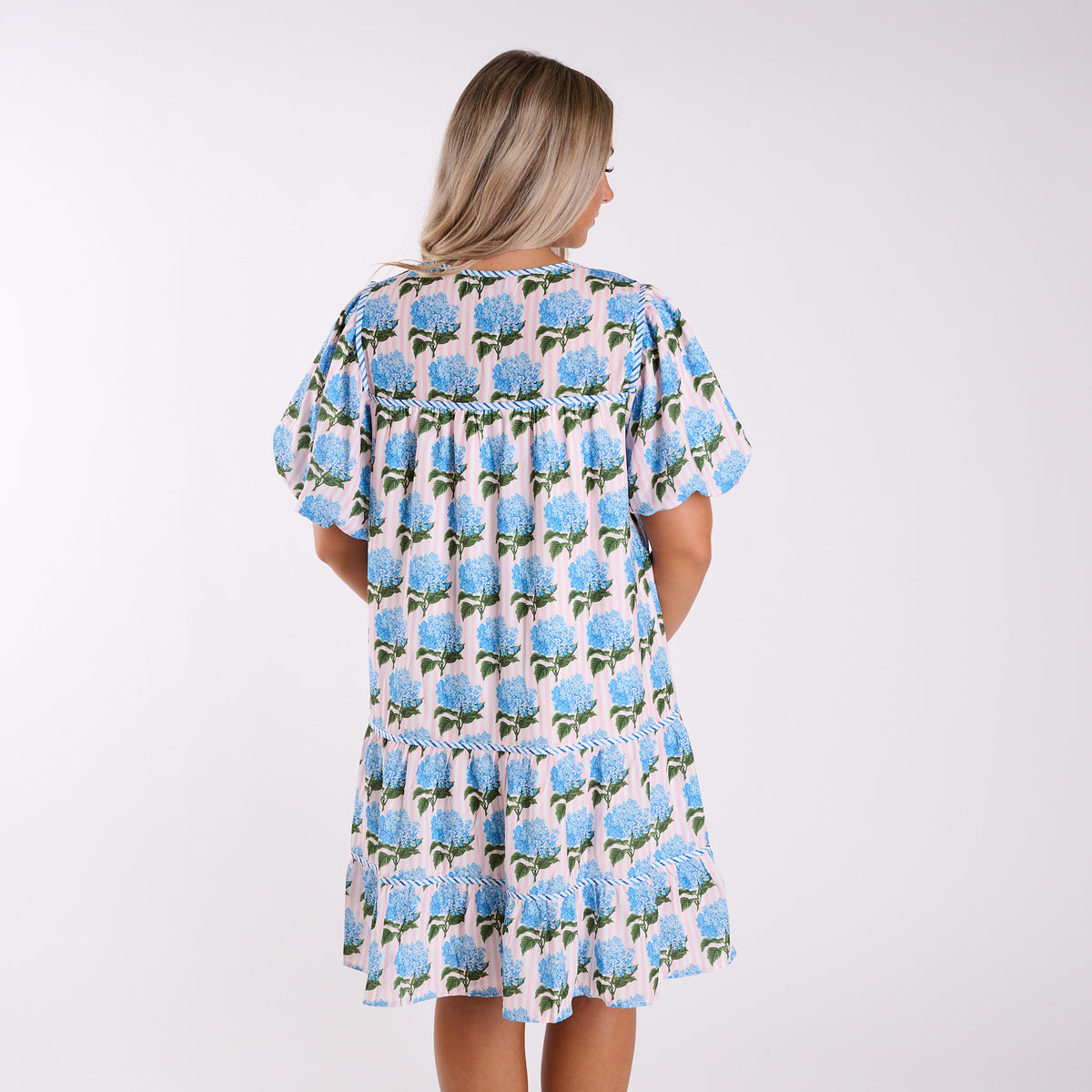 Woman wearing a floral dress with blue flowers on a white background