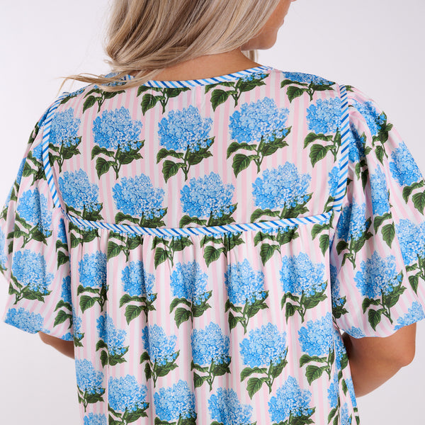 Woman wearing a floral dress with blue hydrangeas on a white background