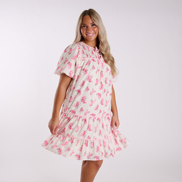 Woman wearing a floral dress with pink flowers on a white background