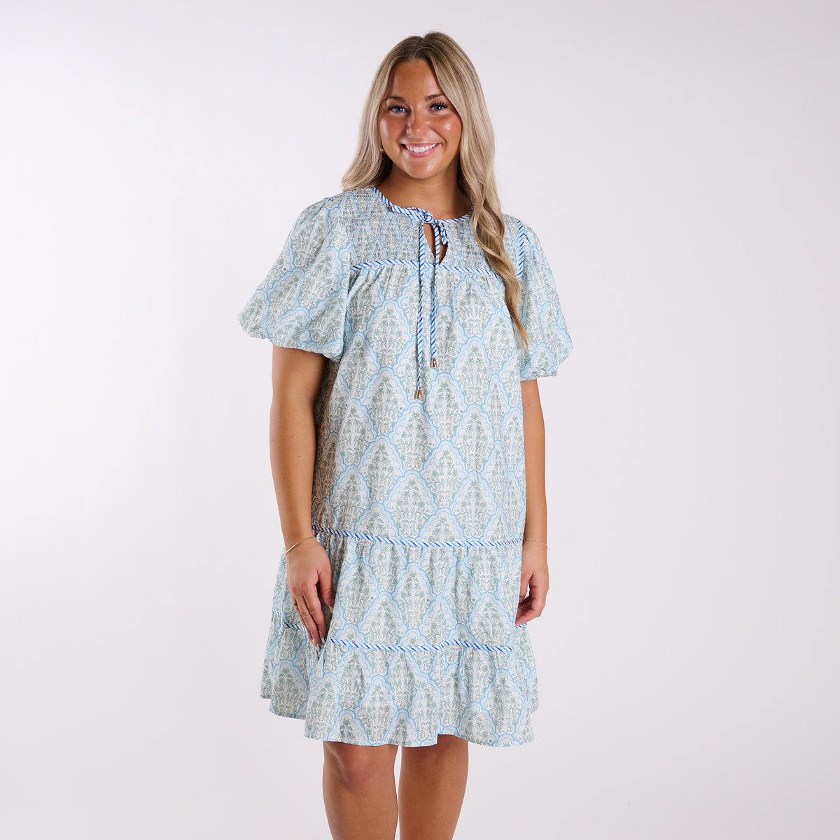 Woman wearing a light blue patterned dress on a white background