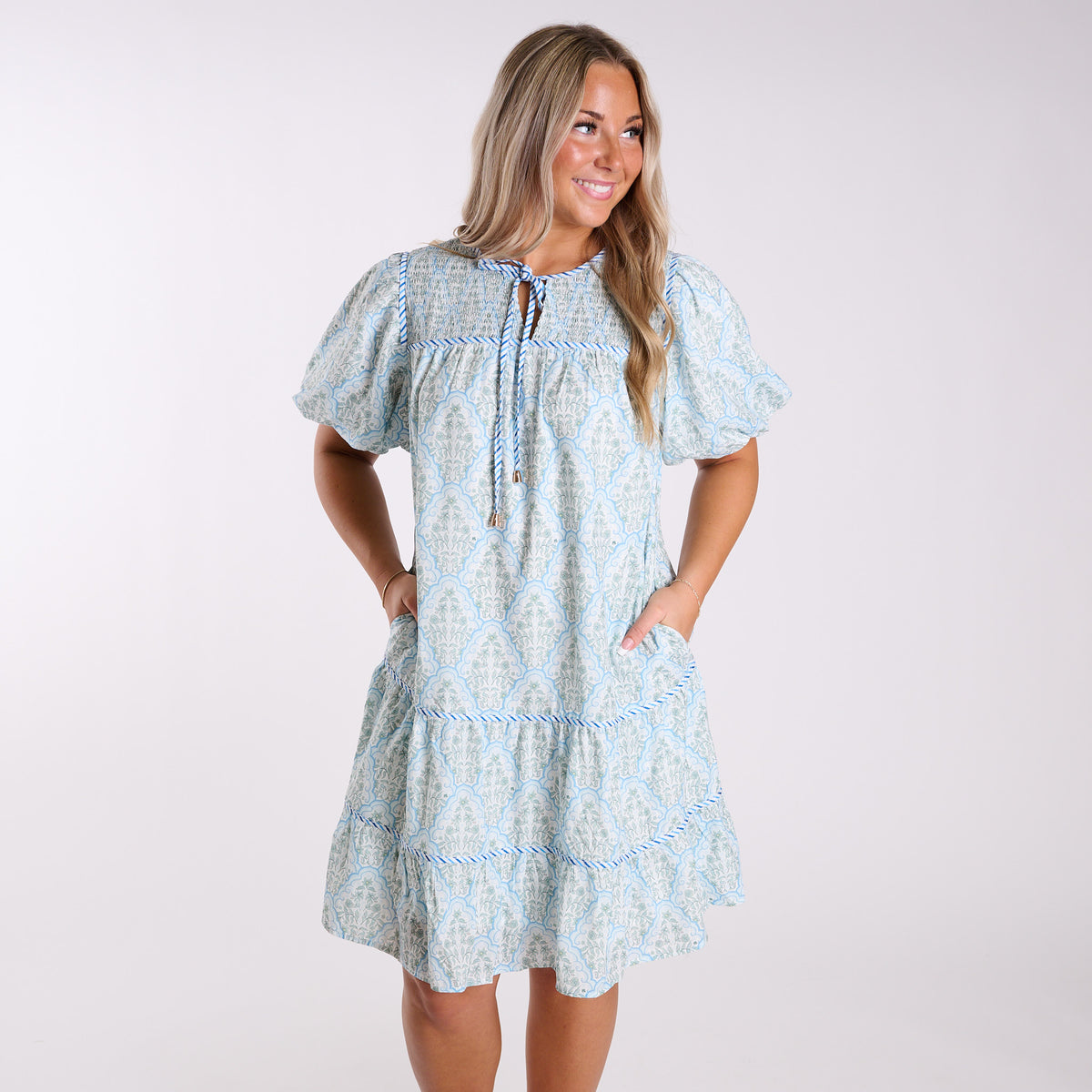 Woman wearing a light blue floral dress against a white background