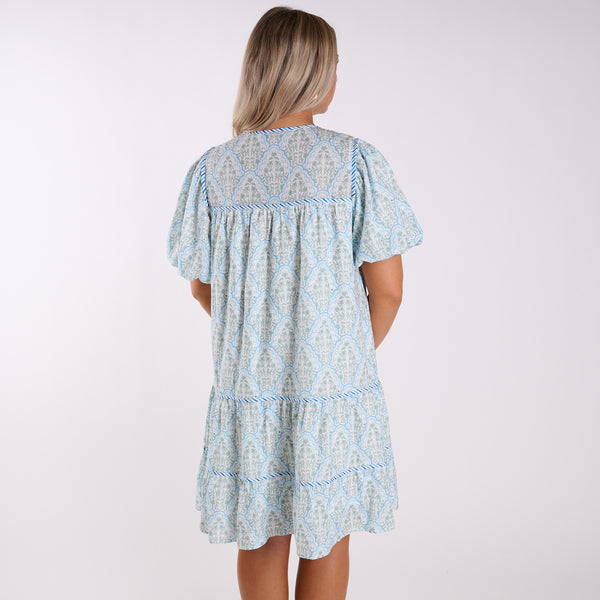 Woman wearing a light blue patterned dress on a white background