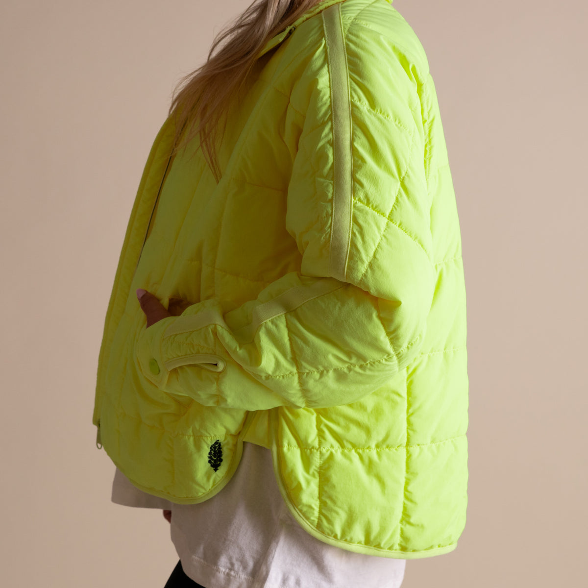 Person wearing a bright yellow puffer jacket on a beige background