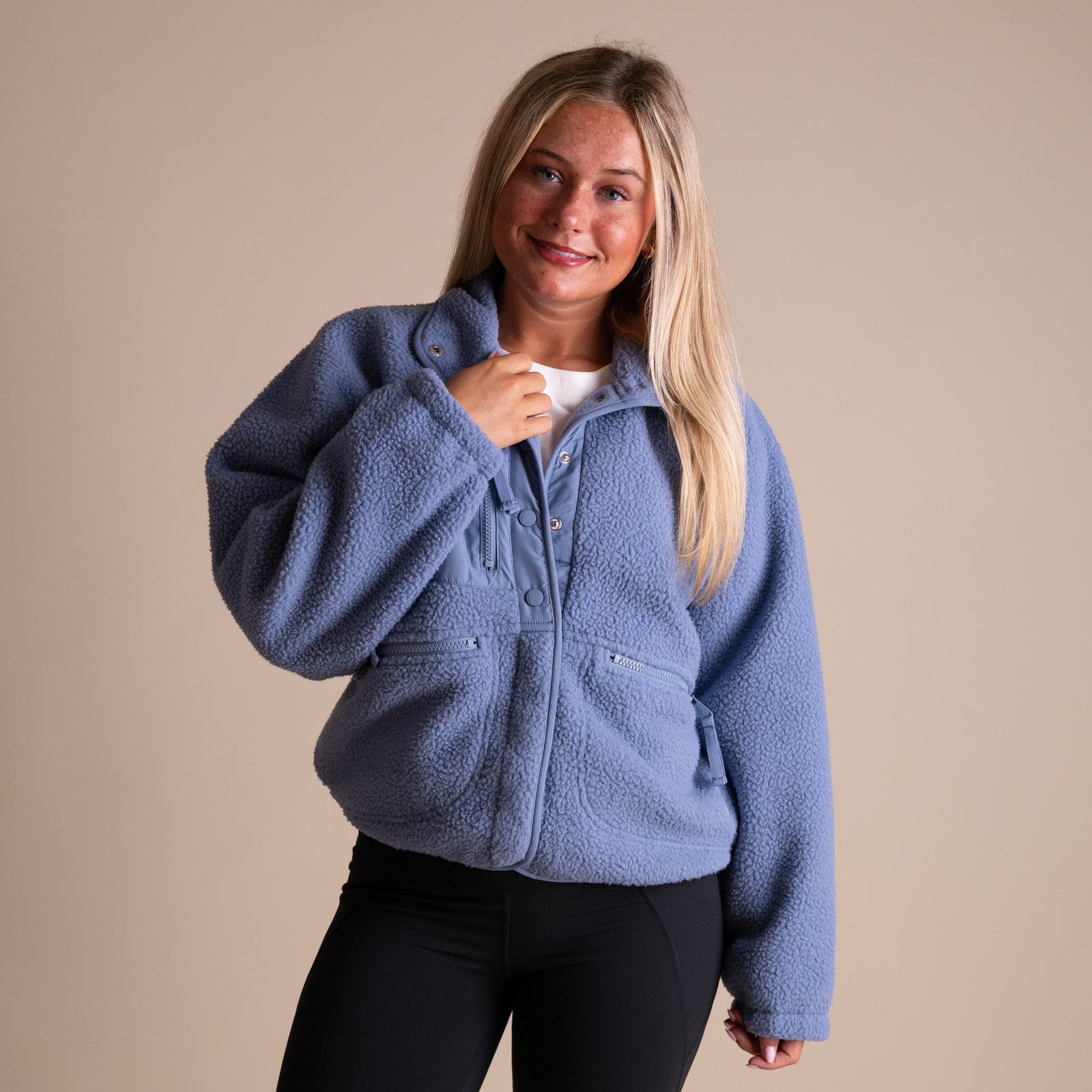 Woman wearing a blue fleece jacket against a beige background