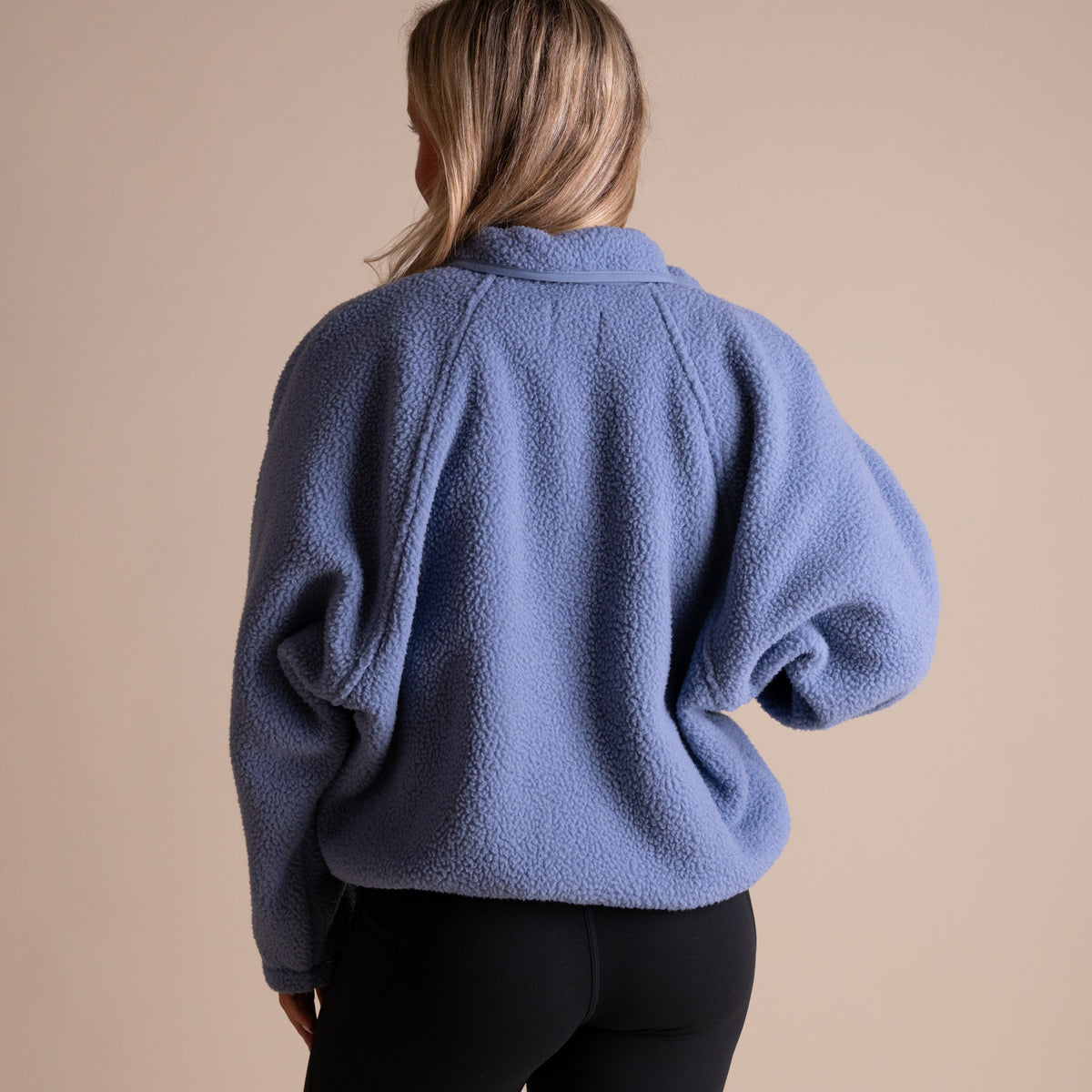 Person wearing a blue fleece jacket on a beige background