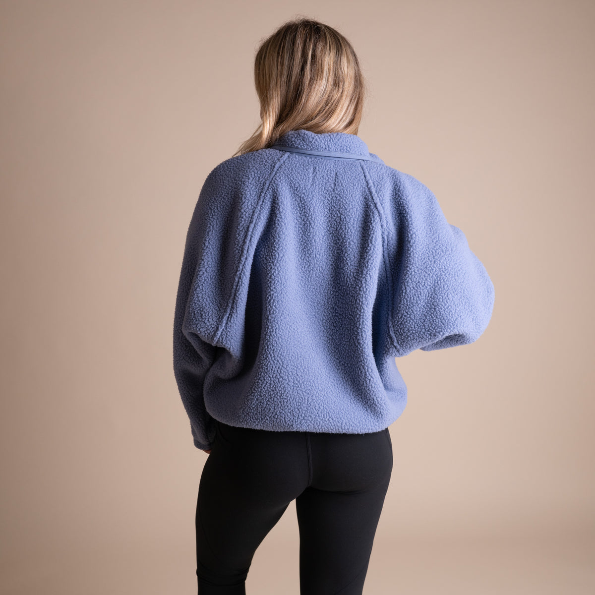 Person wearing a blue fleece jacket on a beige background