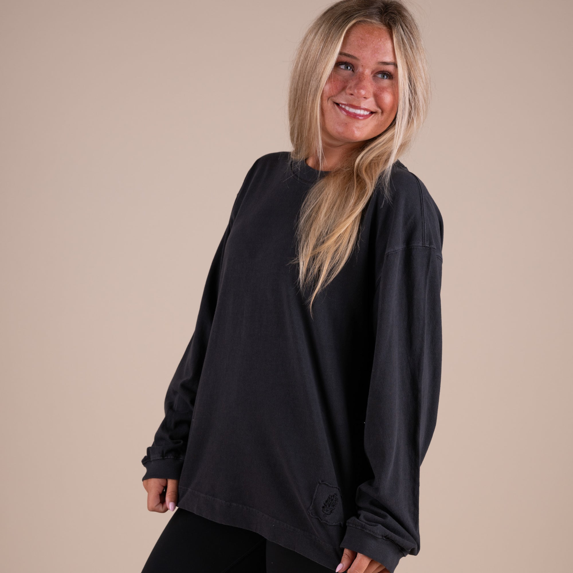 Woman wearing a black long-sleeve top against a beige background