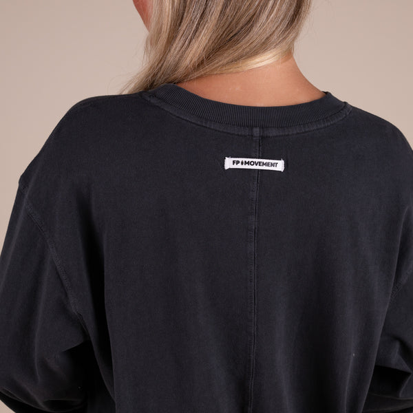 Black sweatshirt with a visible brand label on the back against a neutral background