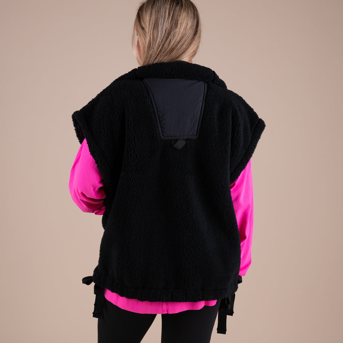 Person wearing a black and pink jacket with a plain background