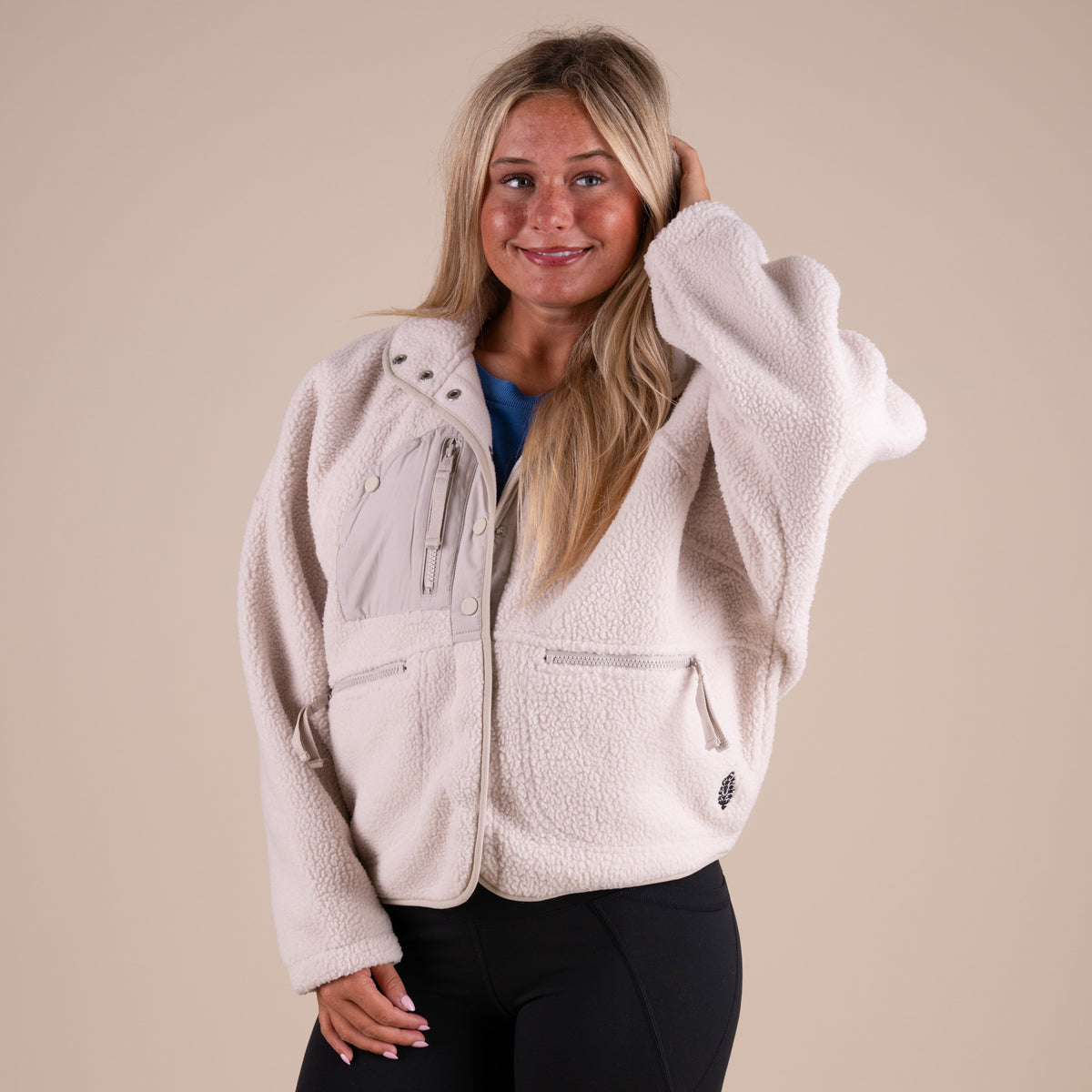 Woman wearing a beige fleece jacket on a beige background