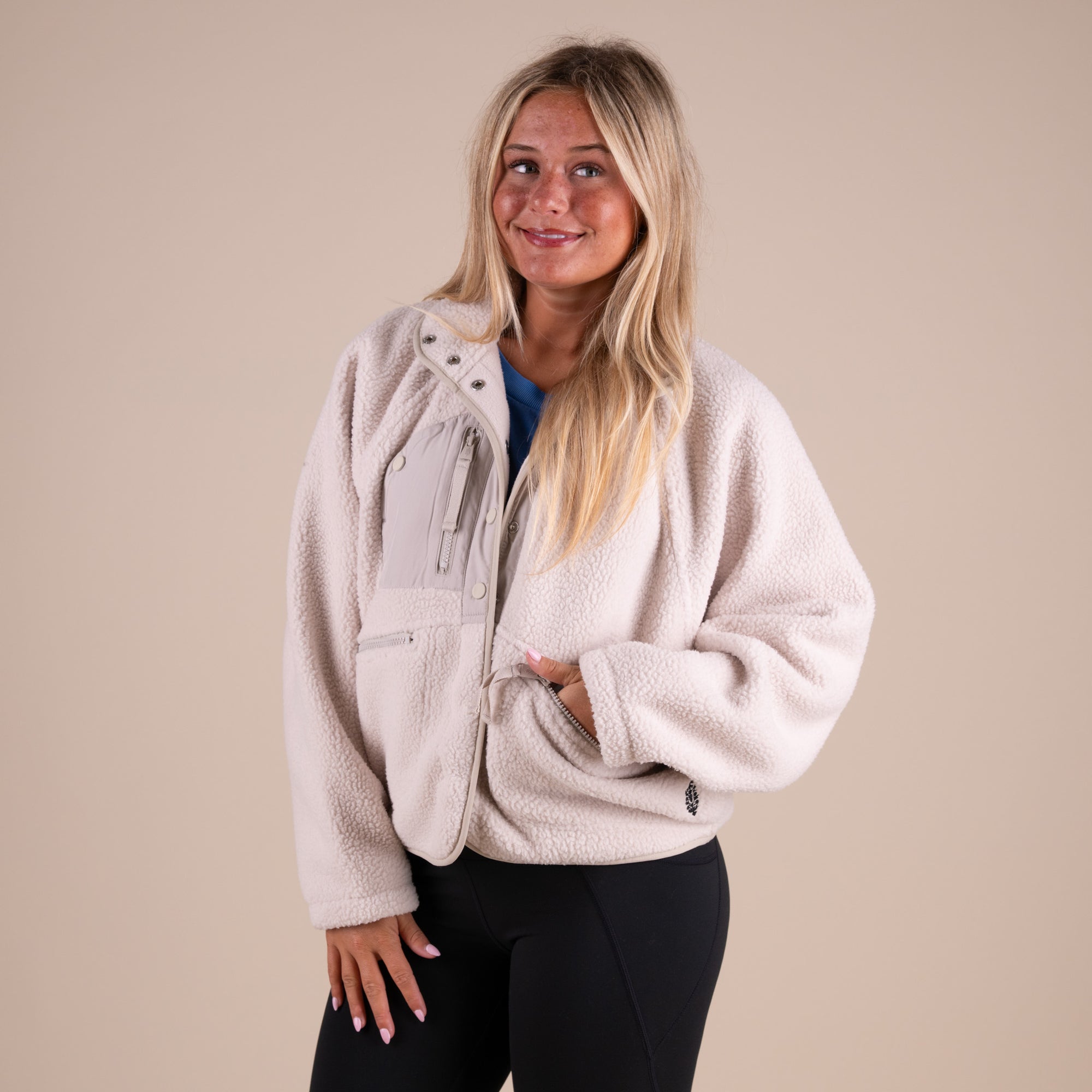 Woman wearing a beige fleece jacket against a beige background