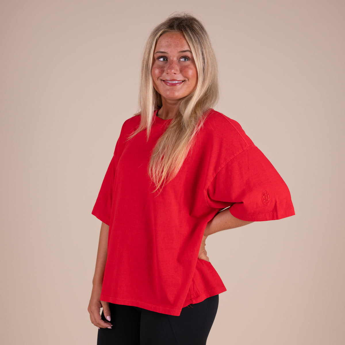 Woman wearing a red shirt against a beige background