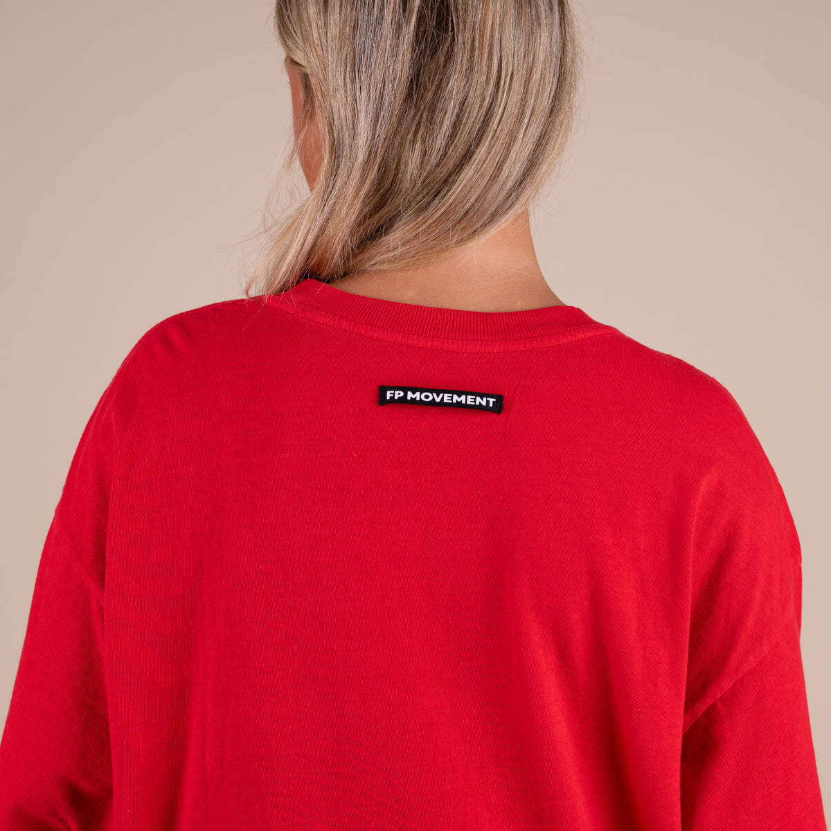 Red sweatshirt with a small black label on the back against a beige background