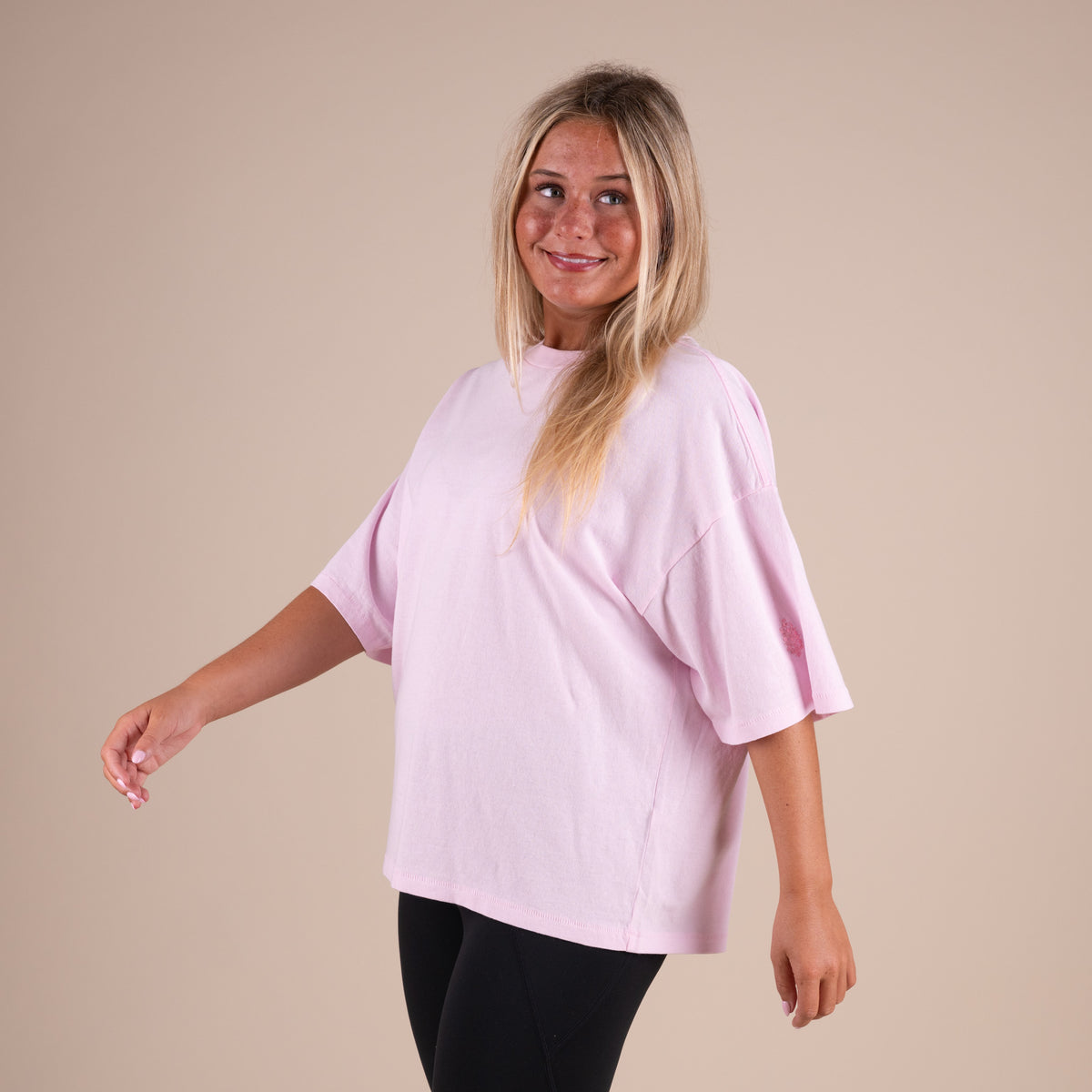 Woman wearing a light pink top against a beige background