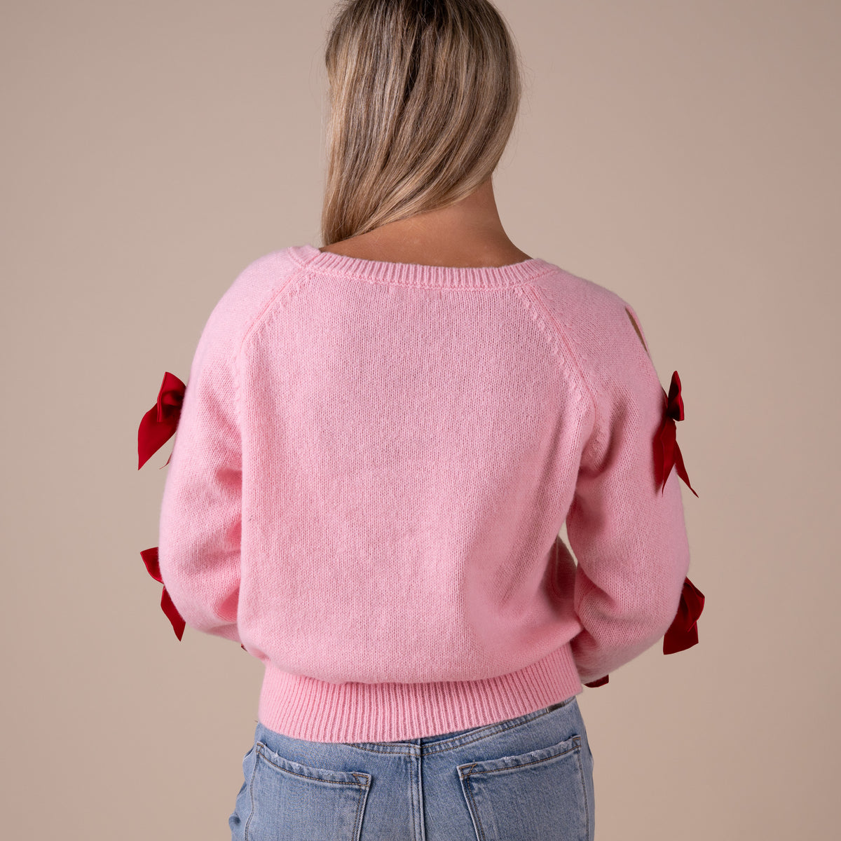 Pink sweater with red bows on a beige background