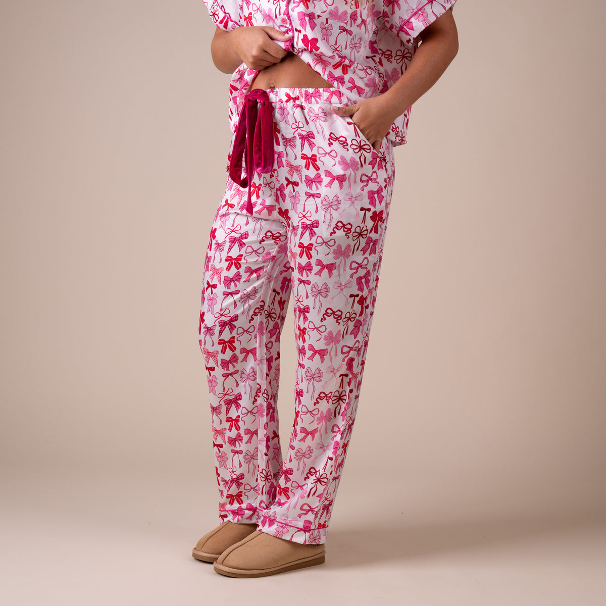 Side view of women’s pink and red bow print pajama pants with elastic waistband and relaxed silhouette.