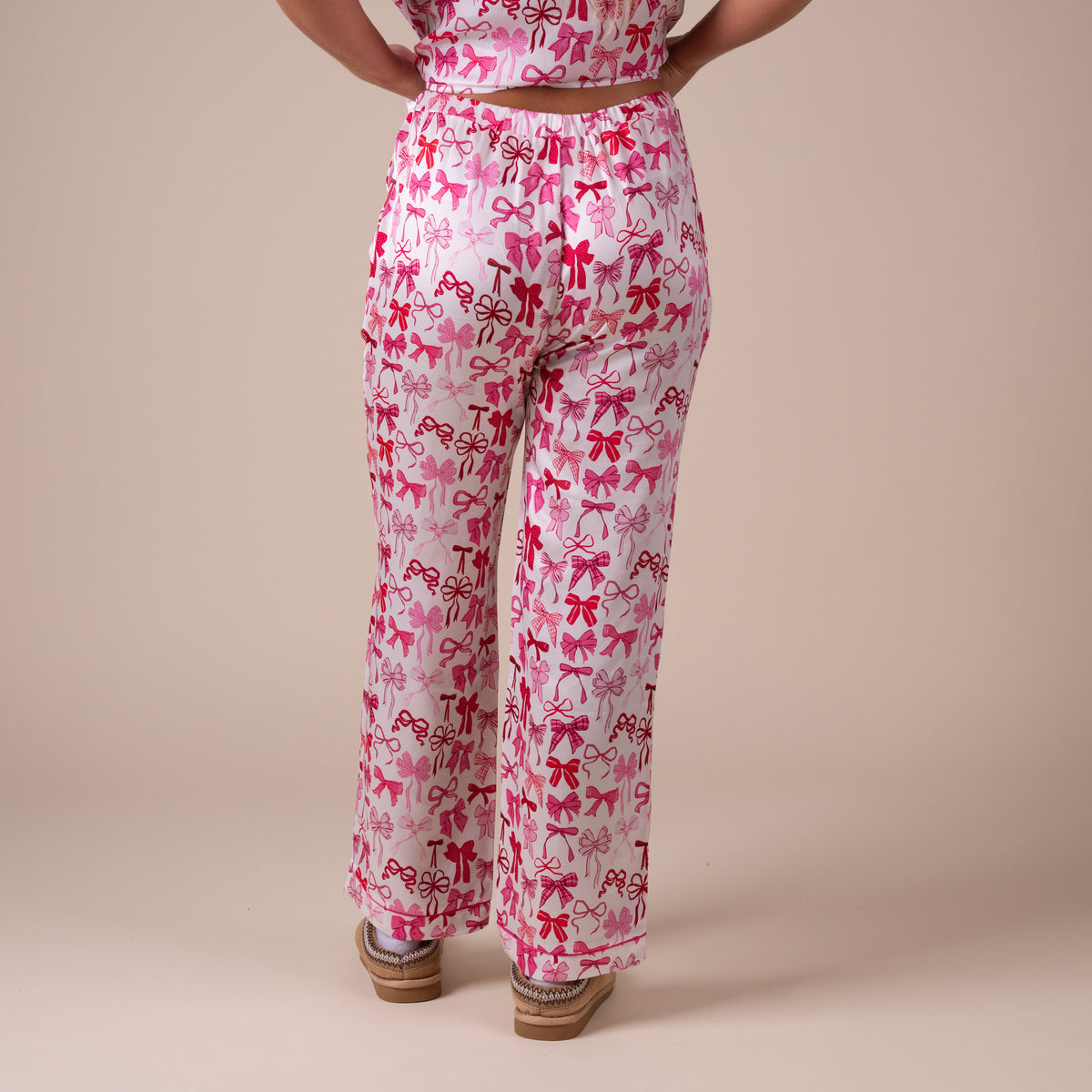 Front view of pink bow print pajama pants featuring velvet drawstring waist and side pockets.