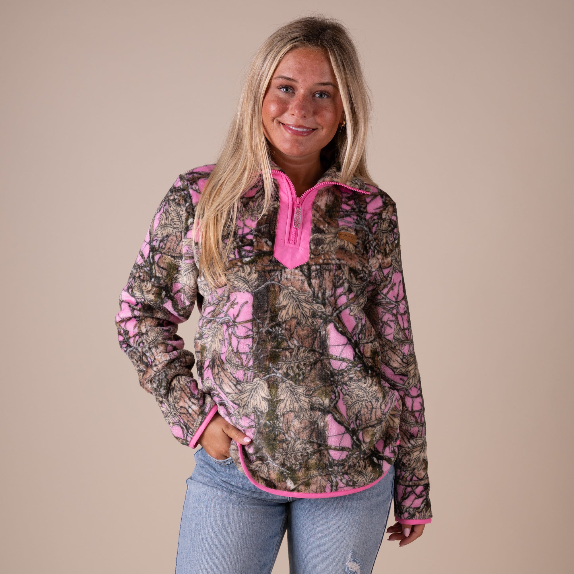 Woman wearing a pink and camouflage jacket on a beige background