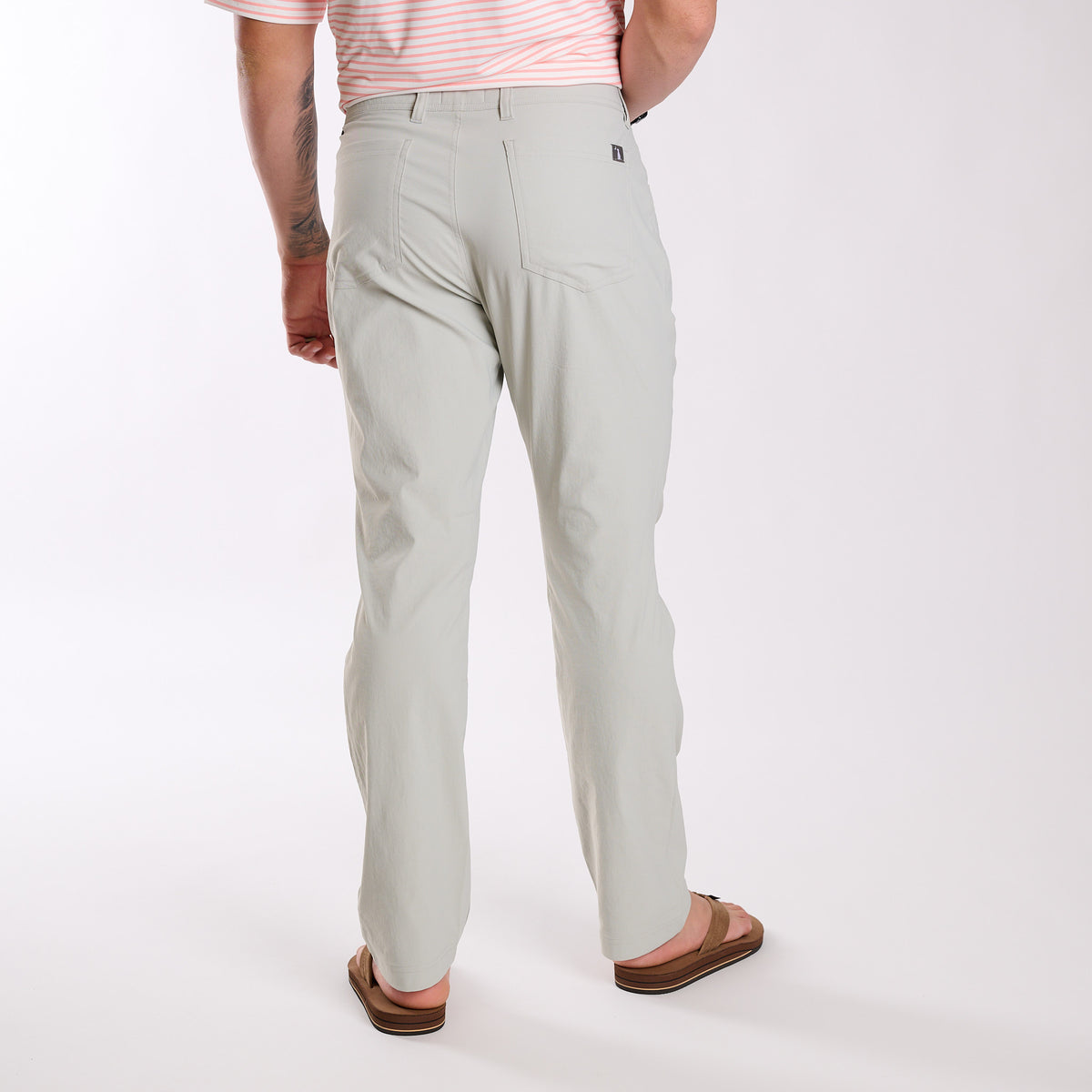 Man wearing Local Boy Outfitters Commuter Pants 2.0 in Cool Grey standing in front of a white background.