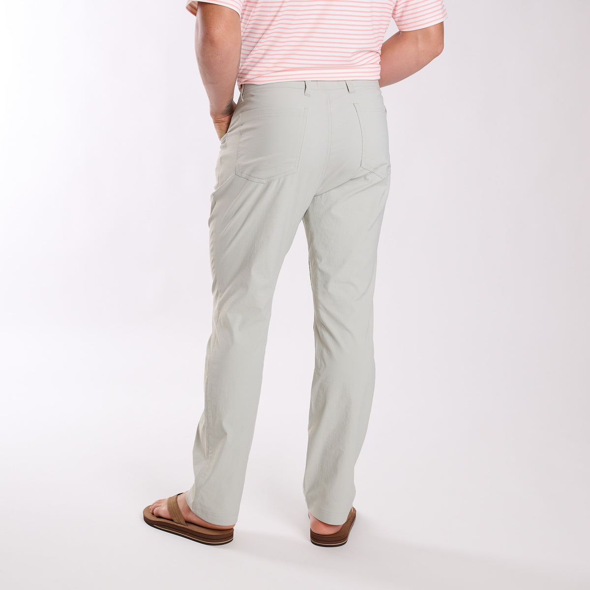 Man wearing Local Boy Outfitters Commuter Pants 2.0 in Cool Grey standing in front of a white background.
