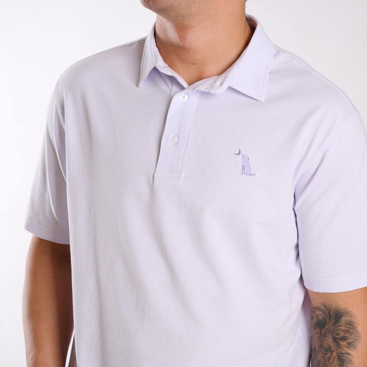 Close up of dog and moon chest emblem on purple and white striped polo.