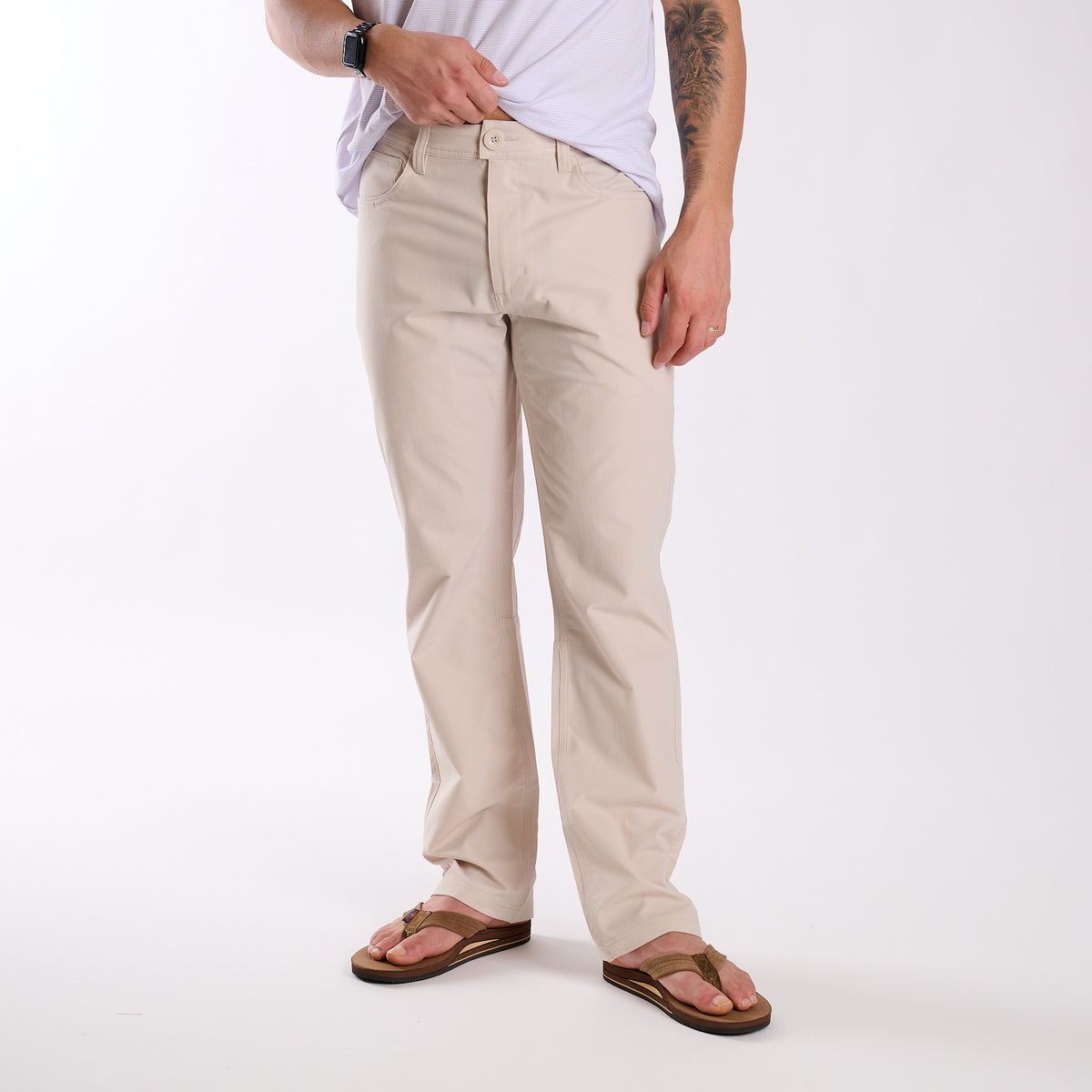 Man wearing Local Boy Outfitters Commuter Pants 2.0 in Light Khaki in front of a white background