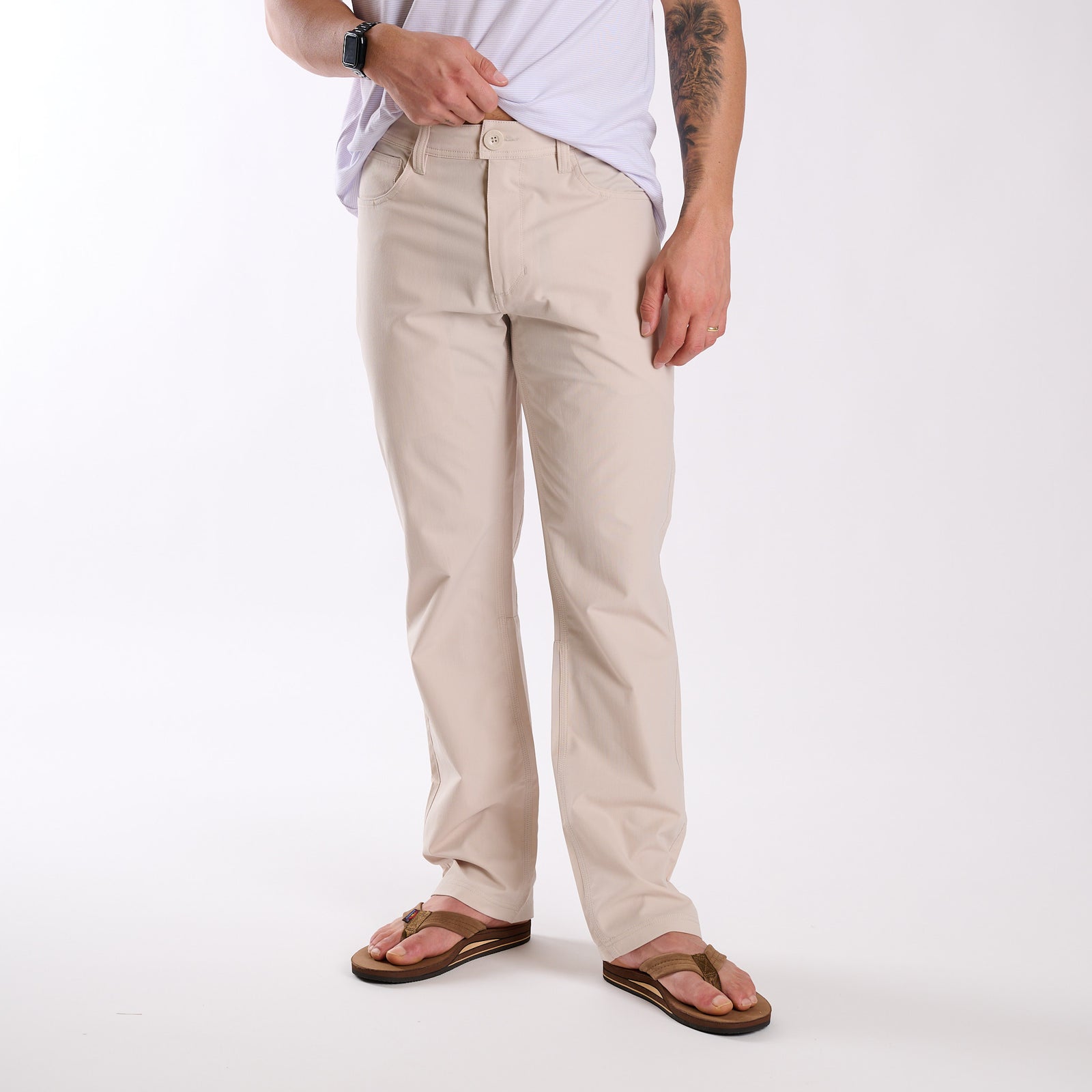Man wearing Local Boy Outfitters Commuter Pants 2.0 in Light Khaki in front of a white background