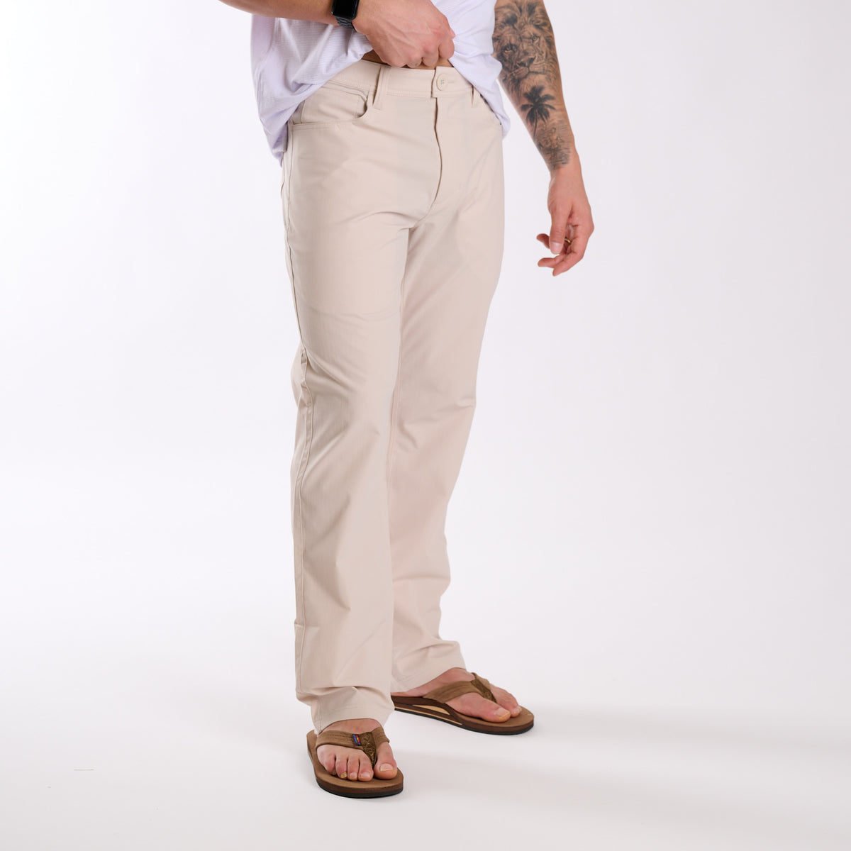 Man wearing Local Boy Outfitters Commuter Pants 2.0 in Light Khaki in front of a white background