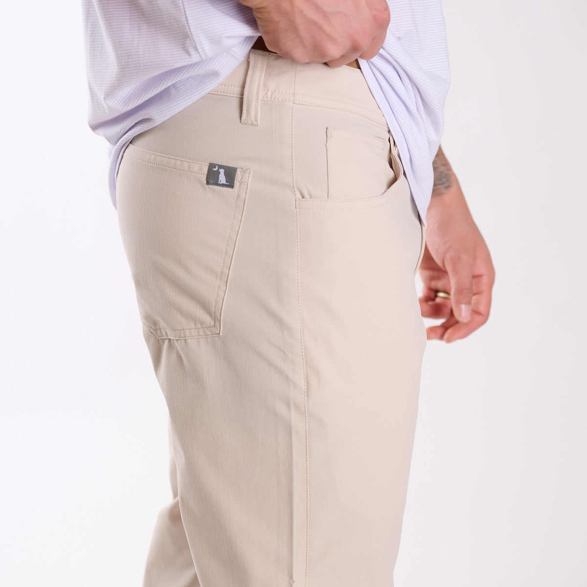 Man wearing Local Boy Outfitters Commuter Pants 2.0 in Light Khaki in front of a white background