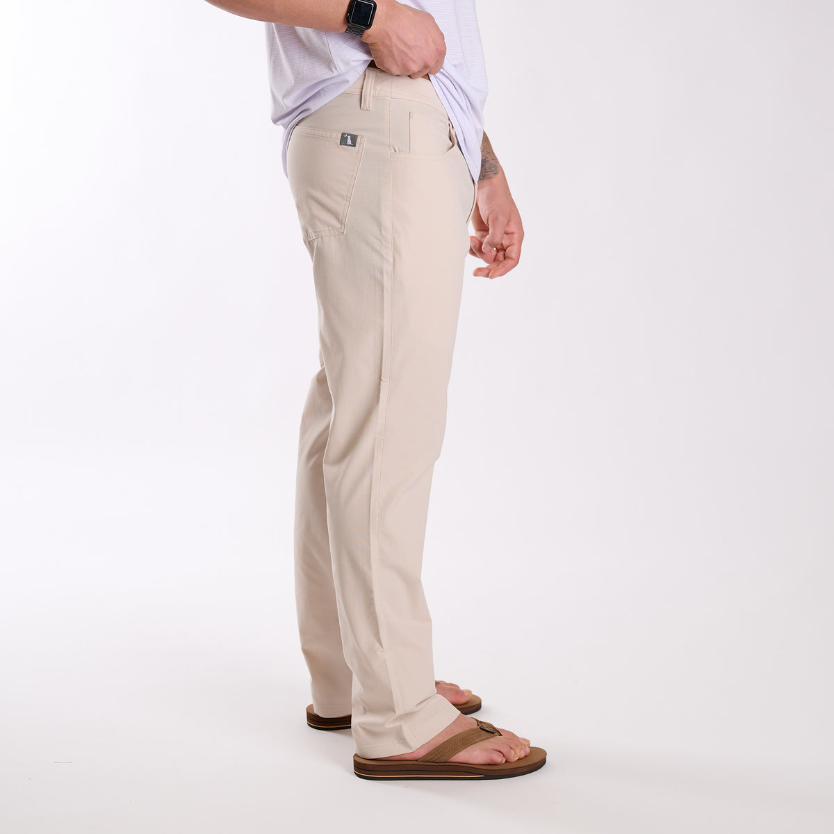 Man wearing Local Boy Outfitters Commuter Pants 2.0 in Light Khaki in front of a white background