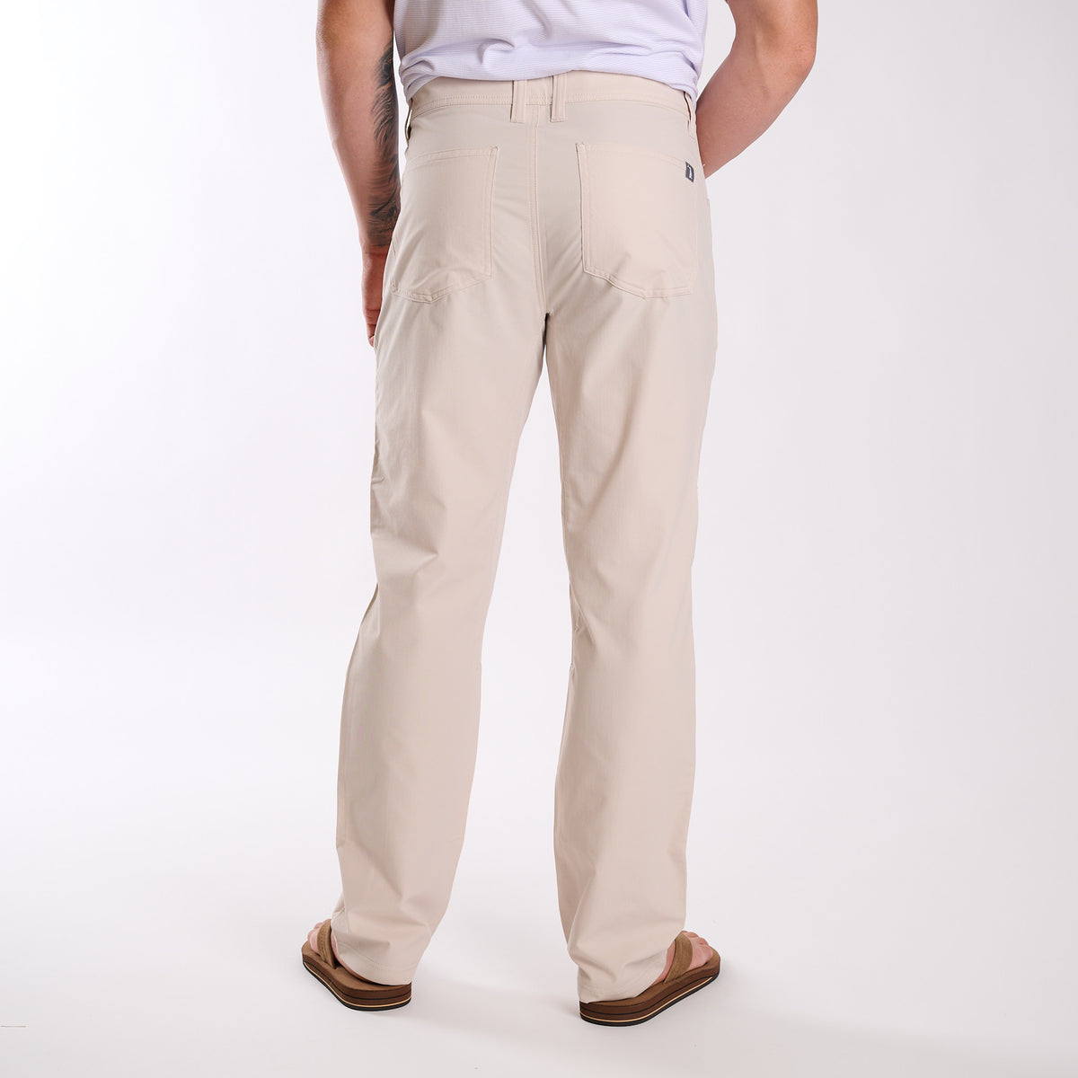 Man wearing Local Boy Outfitters Commuter Pants 2.0 in Light Khaki in front of a white background