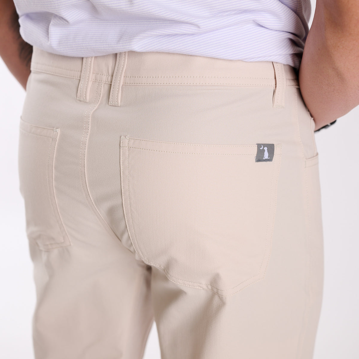 Man wearing Local Boy Outfitters Commuter Pants 2.0 in Light Khaki in front of a white background
