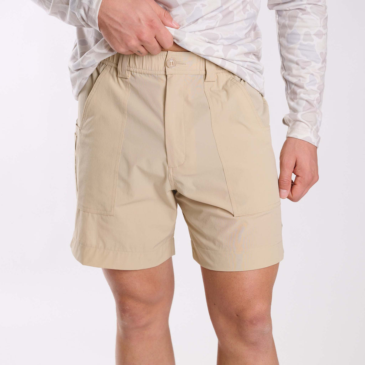Man wearing Local Boy Outfitters chum shorts in light khaki on a white background