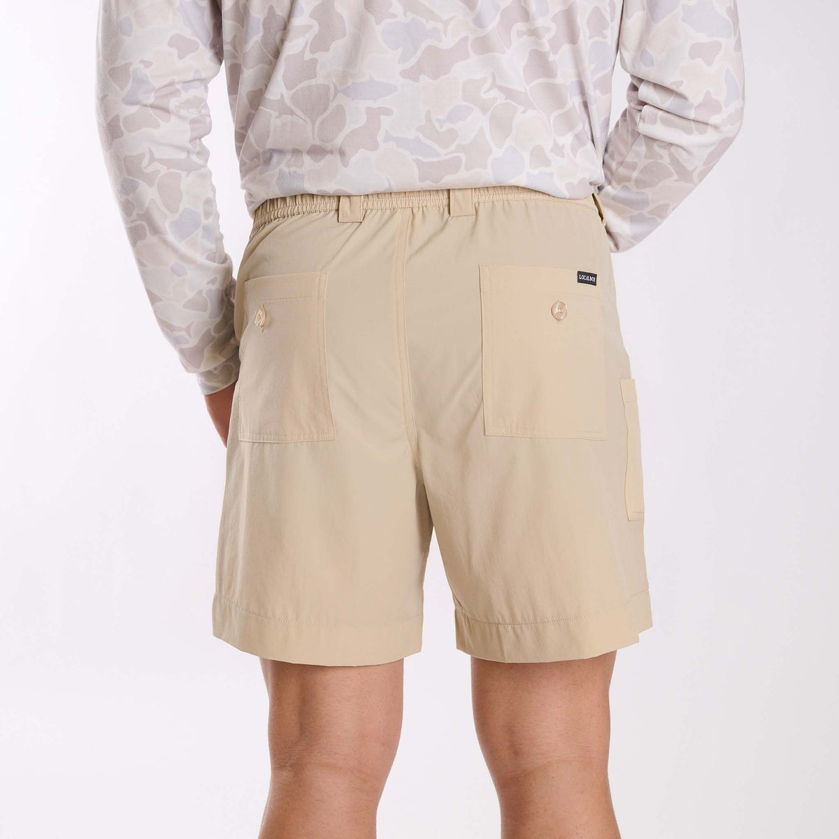 Man wearing Local Boy Outfitters chum shorts in light khaki on a white background