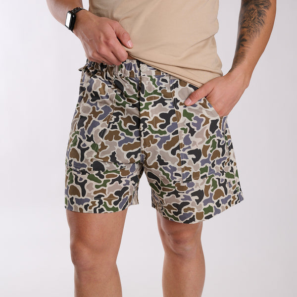 Man wearing local boy outfitters 6 Inch Chum Shorts in Localflage camo in front of a white background