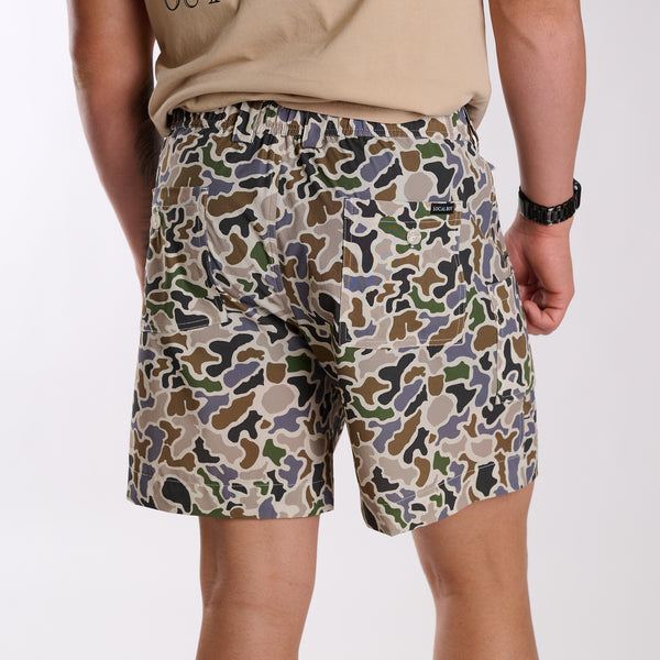 Man wearing local boy outfitters 6 Inch Chum Shorts in Localflage camo in front of a white background