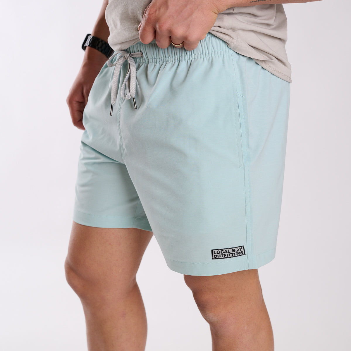 Man wearing Local Boy Outfitters Bayview Swim Trunks in Mint in front of a white backdrop.