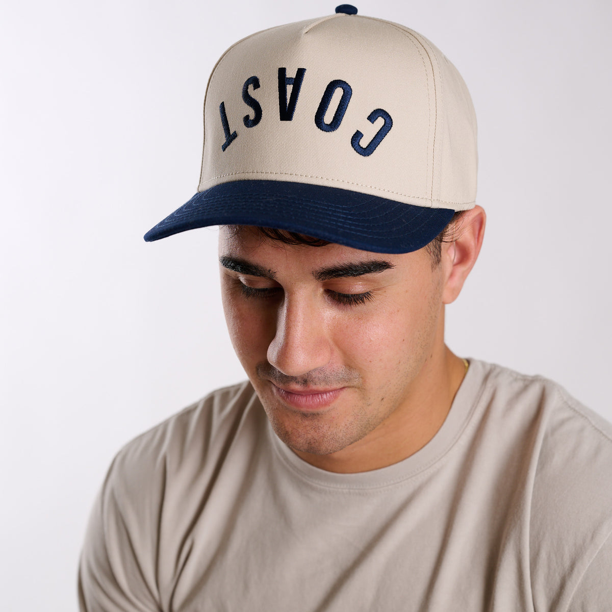 COAST two-tone snapback hat with navy brim and embroidered lettering, front view on model