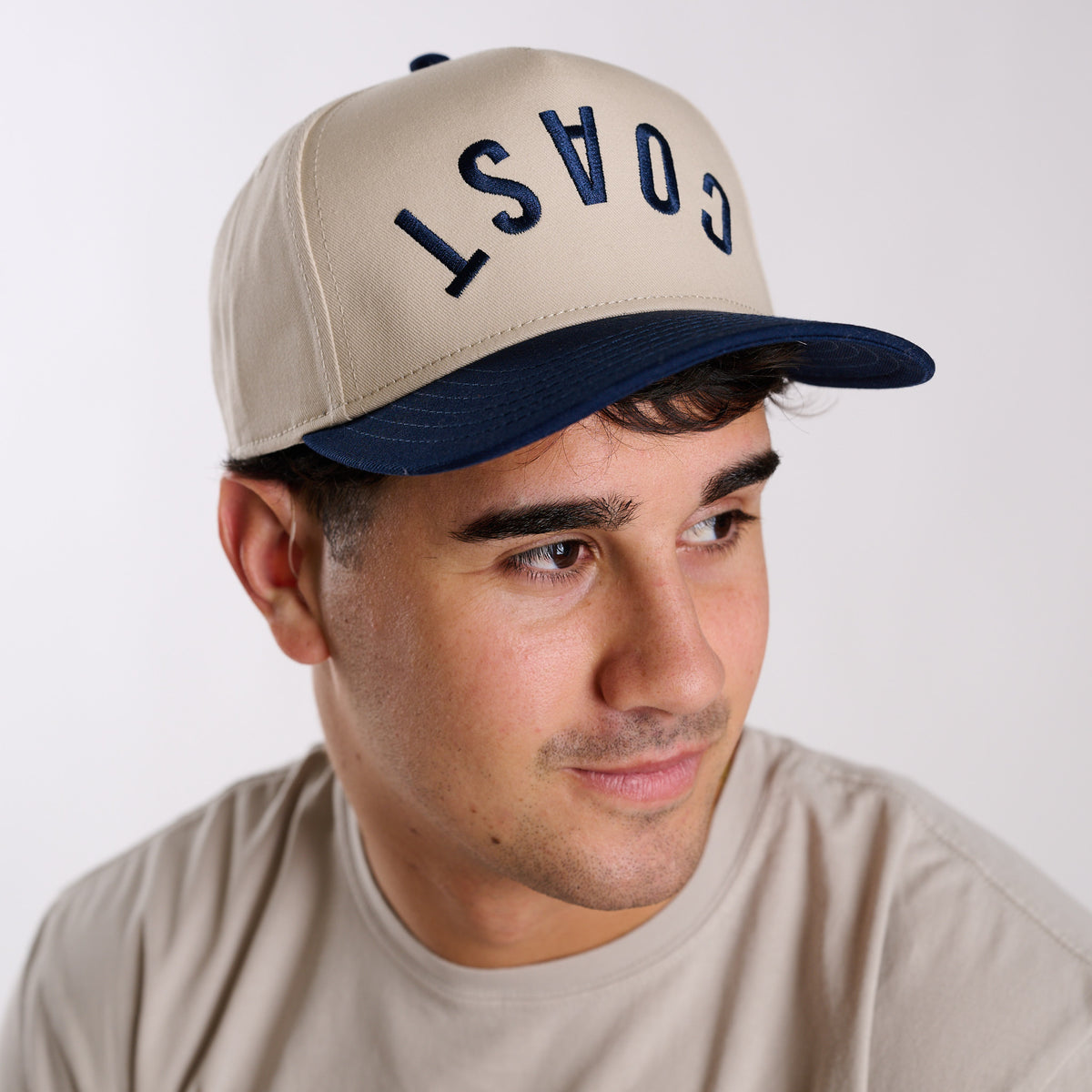 COAST two-tone snapback hat with navy brim and embroidered lettering, front view on model