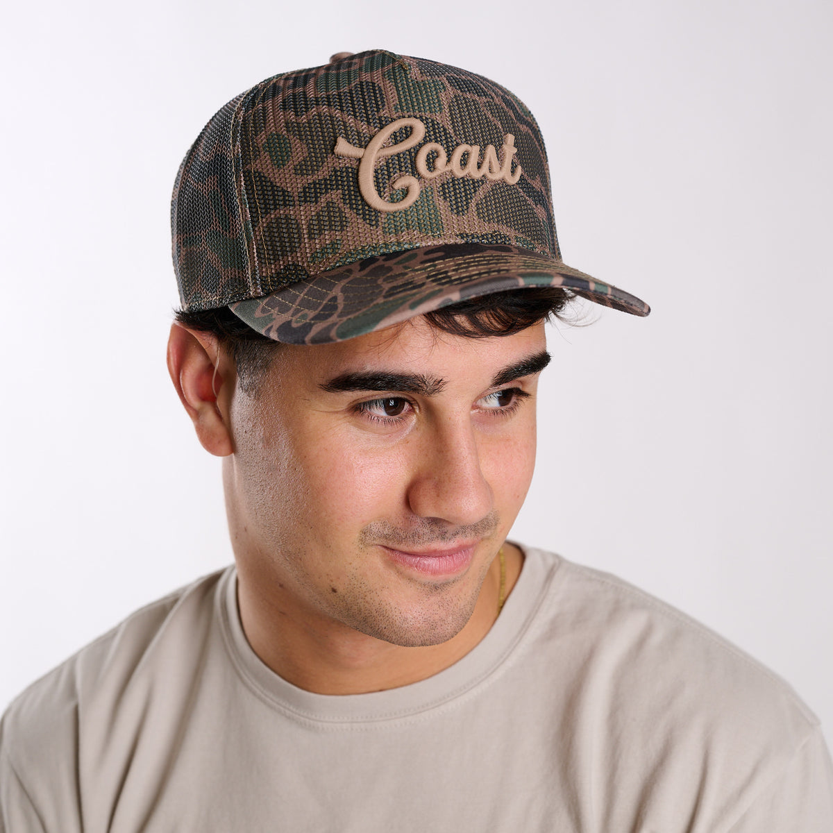 Man wearing a camouflage cap with 'Coast' text on a white background