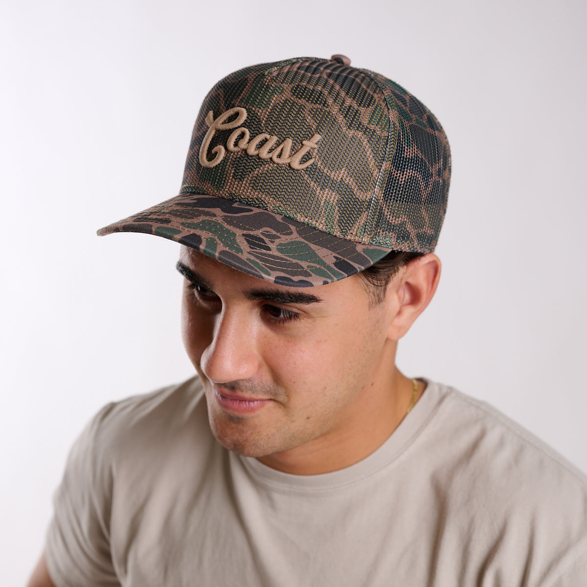 Man wearing a camouflage cap with 'Coast' text on a white background