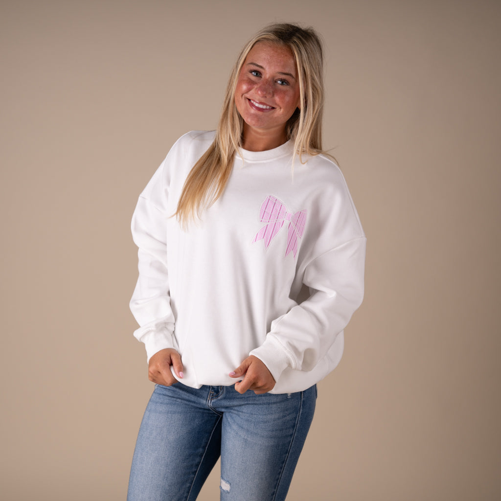 White crewneck sweatshirt with large pink striped bow graphic on back and small matching bow on front.