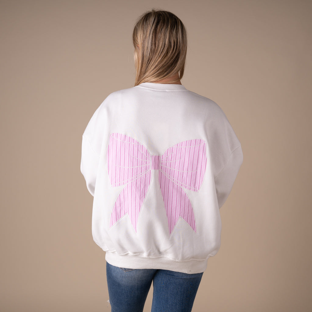 White crewneck sweatshirt with large pink striped bow graphic on back and small matching bow on front.
